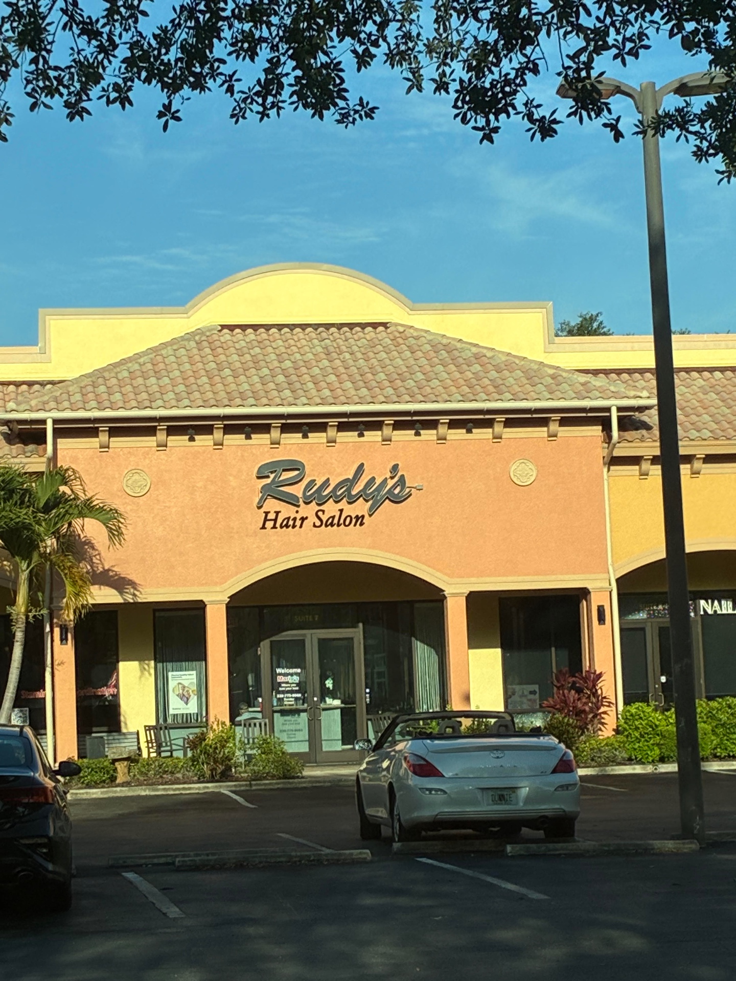 Rudy's Hair Salon storefront at Sugden Park Plaza — terracotta stucco with arched entrance